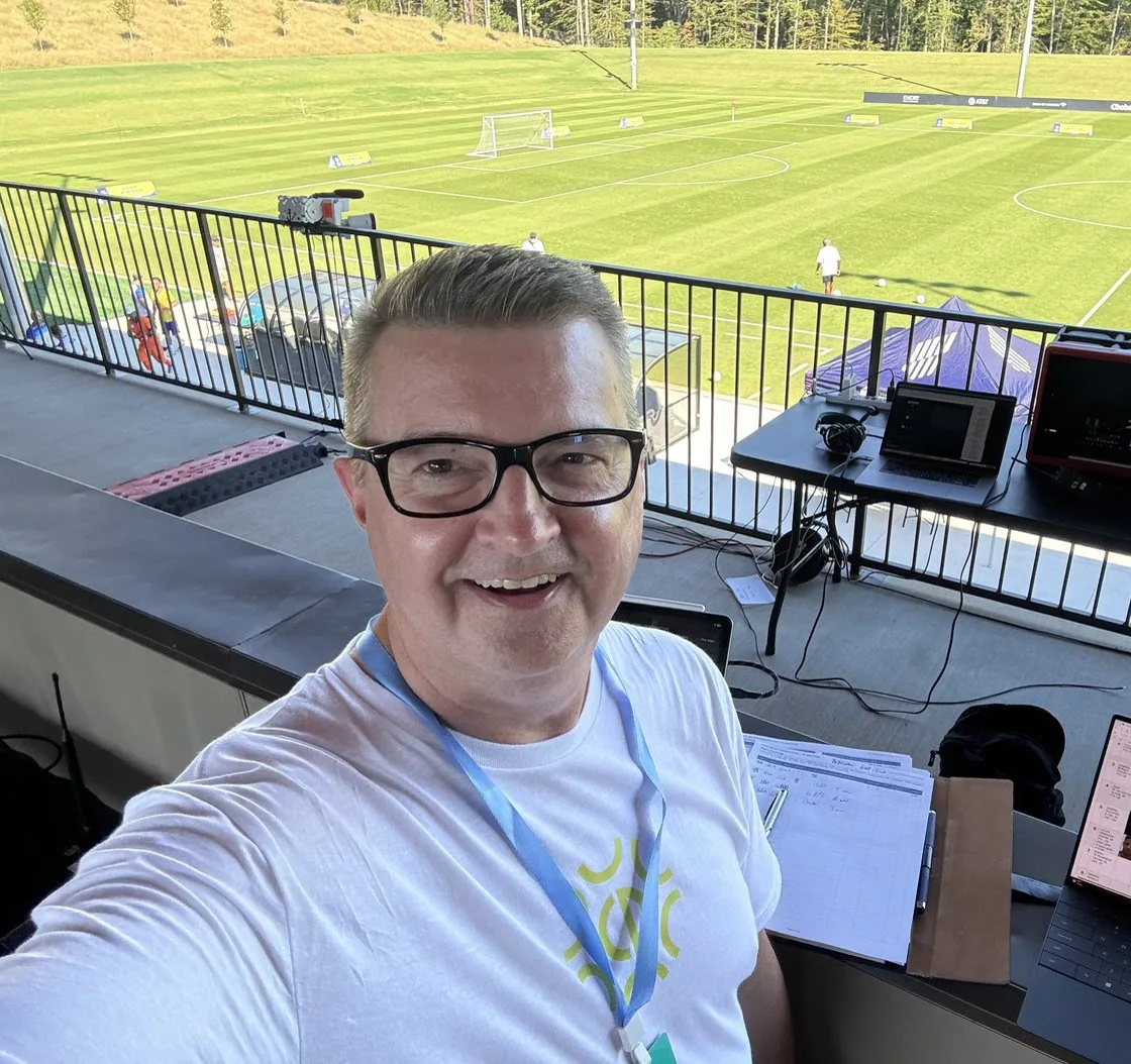 Greg Gibbs in the announcer's booth overlooking a soccer pitch at the U.S. Soccer National Training Center